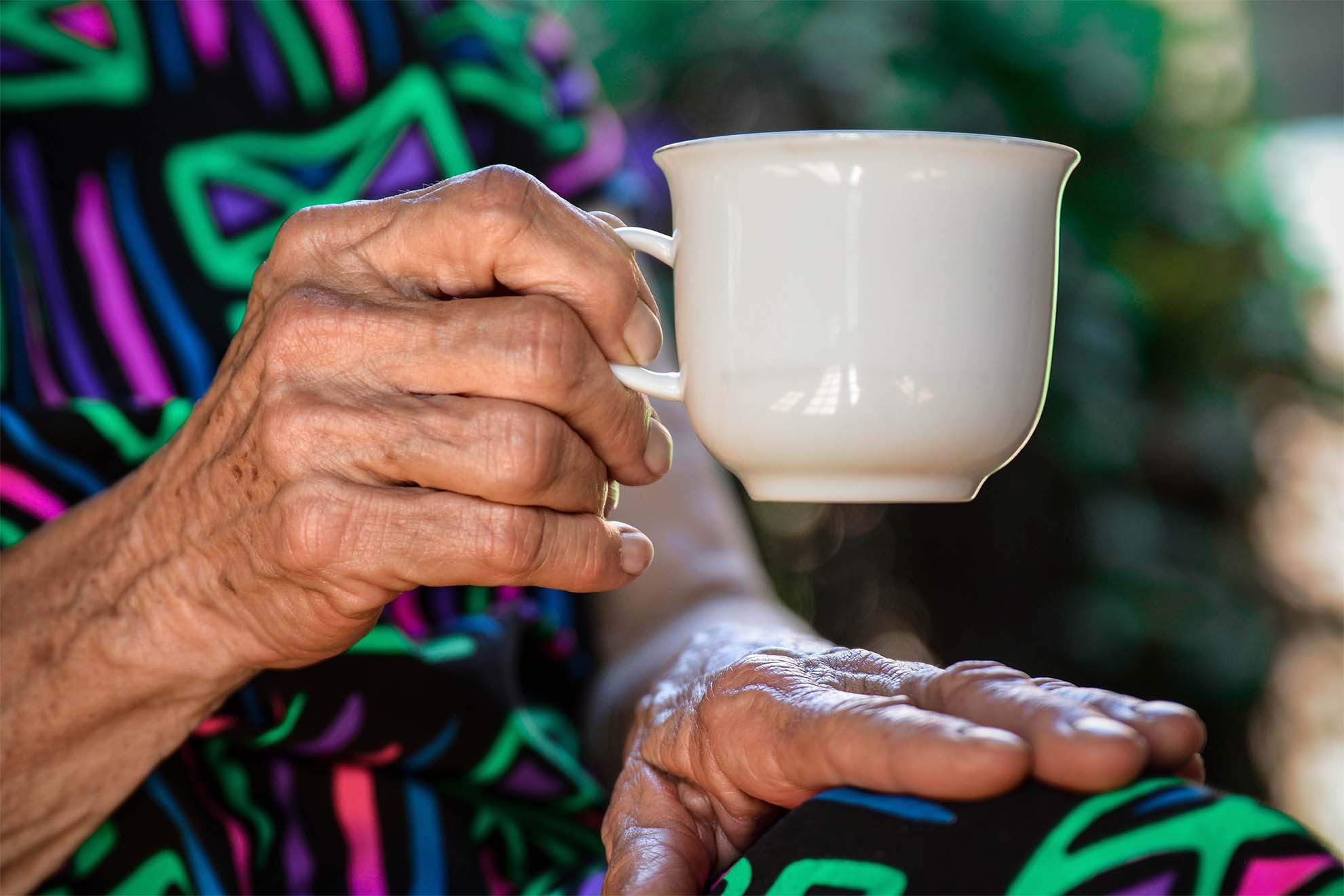 elderly hand holding a mug